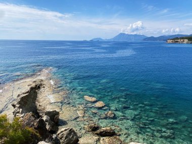 Phaselis kıyısındaki dağların ve kayaların panoramik manzarası güneşli havada Kemer yakınlarındaki Akdeniz 'in mavi ve berrak suyuyla. Antalya, Türkiye.