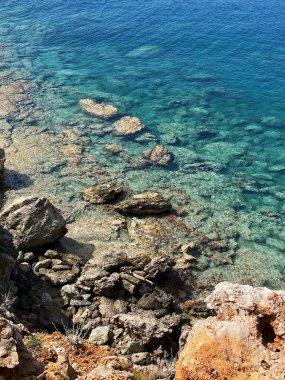 Güneşli bir havada, Akdeniz 'in mavi ve berrak sularıyla Phaselis kıyısındaki dağların ve kayaların manzarası. Antalya, Türkiye.