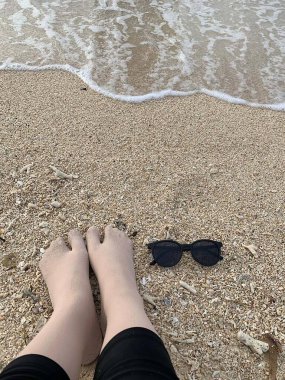 The photo captures someone's sock-clad feet standing on the edge of the beach, blending cozy warmth with the seaside chill