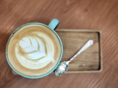 Tahta bir masada kaşıkla bir fincan kahvenin üstünden çekilmiş..