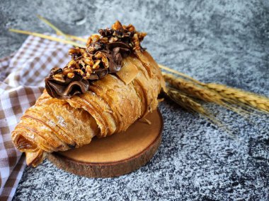 Tahta kesme tahtasının üzerinde çikolata parçacıklı bir kruvasan..