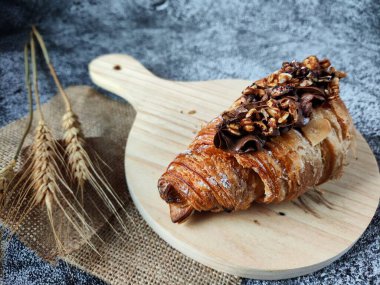 Tahta kesme tahtasının üzerinde çikolata parçacıklı bir kruvasan..