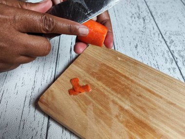 Tahta kesme tahtasıyla havuç kesen kadın.