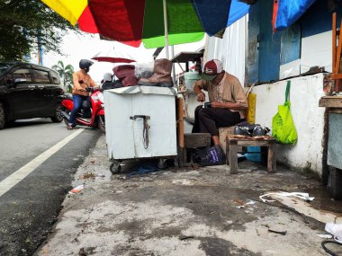 Balikpapan-Doğu Borneo 18 Ağustos 2024, Shoemaker yol kenarındaki ayakkabıları onarıyor