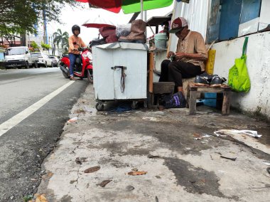 Balikpapan-Doğu Borneo 18 Ağustos 2024, Shoemaker yol kenarındaki ayakkabıları onarıyor