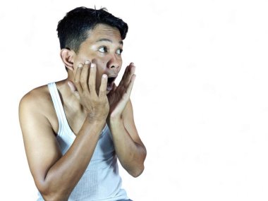 Yalnız beyaz arka planda duran genç, yakışıklı bir adam korku, korku ve heyecan dolu bir yüz ifadesinden korkuyor ve şoka uğruyor..