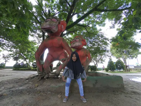 stock image little Asian girl taking photo in front of monkey statue