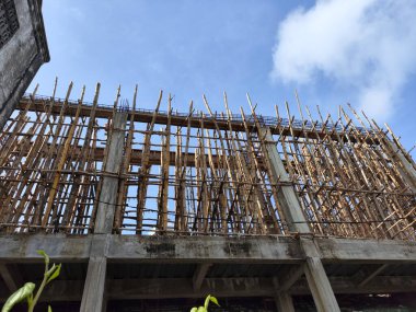 Güneşli mavi gökyüzüne karşı inşaat halinde olan bir cami. Etrafı ahşap iskelelerle çevrili. Düşük açılı çekim.