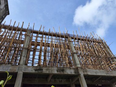 Güneşli mavi gökyüzüne karşı inşaat halinde olan bir cami. Etrafı ahşap iskelelerle çevrili. Düşük açılı çekim.