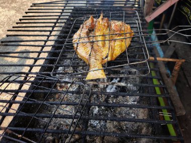 Izgarada bir balık ızgara kömürde kızartılıyor..