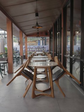 Balikpapan-Doğu Kalimantan Kasım 02.2024 Kapalı bir açık kafe terası ahşap masalar ve sandalyeler düzgünce dizilmiş, güneşli bir günde Hitam Manis Kafe 'de müşterileri bekliyor.