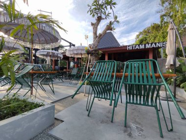 Balikpapan-Doğu Kalimantan Kasım 02.2024 Kapalı bir açık kafe terası. Dev şemsiyeli, masalı ve sandalyeli. Güneşli bir günde Hitam Manis Kafe 'de müşterileri bekliyor.
