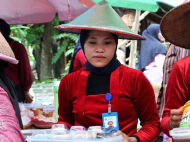 Balikpapan doğusundaki Kalimantan Kasım 03.2024 Endonezyalı kadın gıda satıcısı geleneksel Balikpapan pazarında alıcılara hizmet veriyor