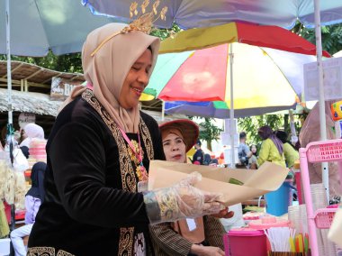 Balikpapan doğusundaki Kalimantan Kasım 03.2024 Endonezyalı kadın gıda satıcısı geleneksel Balikpapan pazarında alıcılara hizmet veriyor