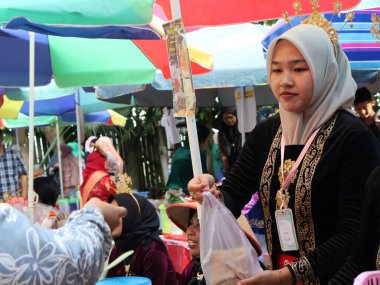 Balikpapan doğusundaki Kalimantan Kasım 03.2024 Endonezyalı kadın gıda satıcısı geleneksel Balikpapan pazarında alıcılara hizmet veriyor