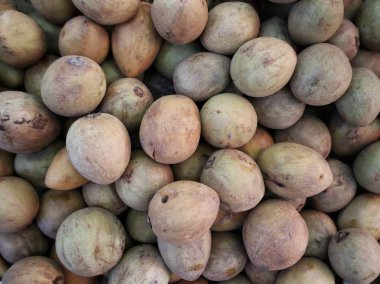 Düz açılı yeşil sapodilla meyvesi yığını Balikpapan 'daki ana meyve pazarında duruyordu.