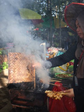 Balikpapan doğusundaki Kalimantan Kasım 03.2024 Izgara satay ya da sıcak kömür üzerine doymuş dumanla çevrili geleneksel sokak yiyeceklerinin otantik hazırlama sürecini gözler önüne seriyor.