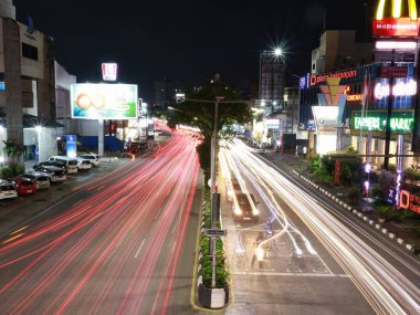 Balikpapan-Doğu Kalimantan Kasım 07.2024, Balikpapan Plaza 'nın önündeki yaya köprüsündeki araçlardan gelen hafif patika. Burası gece fotoğrafçılığının ve uzun pozların favori mekanıdır.