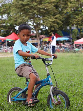 Balikpapan-Doğu Kalimantan 30 Kasım 2024 bisiklete binen çocuk, 5 yaşındaki mutlu çocuk güzel bir sonbahar gününde bisikletle bahar parkında eğleniyor.. 