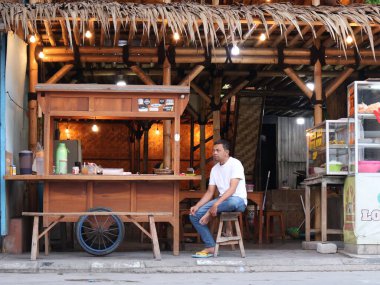 jakarta-Indonesia November 23,2024  a man sit and drink coffe at a street food stall called angkringan clipart