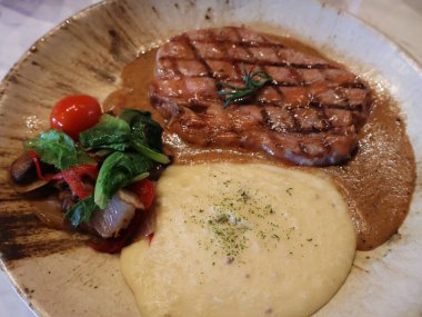 Patates püresi ve sebzeyle servis edilen ızgara kaburga bifteği. Patates püresi ve soslu biftek..