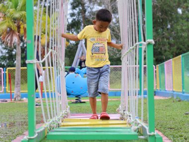 Balikpapan-Doğu Kalimantan Aralık 01.2024 Parkta oynayan Asyalı çocuk, Oyun parkındaki tırmanma parkında eğlenen Asyalı oyuncu çocuk
