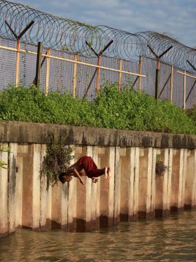 balikpapan-indonesia december 12,2024 Junior schoolboy performed back-flip from pier into azure sea. asian teen doing a back flip into sea clipart