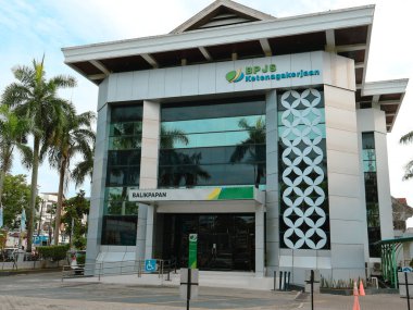 Balikpapan-Endonezya 21 Aralık 2024 BPJS Ketenagakerjaan Balikpapan ana ofisi, modern binanın dış ve tabelaları, erken güneş ışığıyla aydınlatılmıştır.