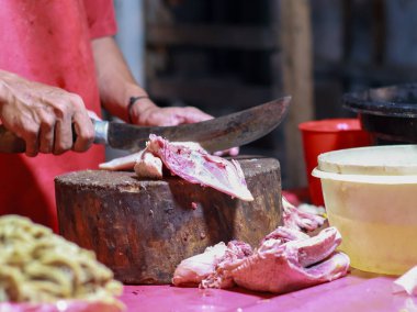 Balikpapan Ocak 04.2025 geleneksel bir pazarda tavuk tüccarı. Balikpapan 'dan bir müşteri tarafından satın alındıktan sonra ağaç gövdesindeki tavuğu kesip temizliyor.