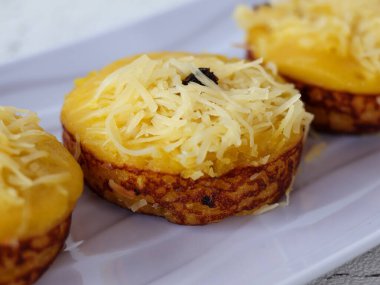 Beyaz tabakta patates bingka 'ya yakın olan Bingka, kahverengi tartan peçetesi üzerinde beyaz bir tabakta servis edilen Kalimantan bölgesinin (Endonezya) tatlısıdır.. 