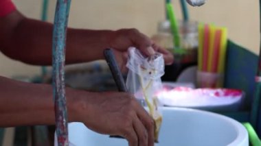 A 'Dawet' buz satıcısı, alıcının sipariş ettiği buzu plastik torbaya, Endonezya 'nın buzlu Hindistan cevizi içeceğine ya da buzlu Dawet' e yerleştiriyor.