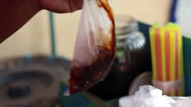 A 'Dawet' buz satıcısı, alıcının sipariş ettiği buzu plastik torbaya, Endonezya 'nın buzlu Hindistan cevizi içeceğine ya da buzlu Dawet' e yerleştiriyor.