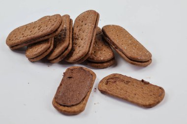 Balikpapan-Endonezya Şubat 01.2025 Bir yığın lezzetli kahverengi buğday yuvarlak bisküvisi Beyaz arka planda birkaç kırıntı izole, lezzetli gevrek yuvarlak krakerler