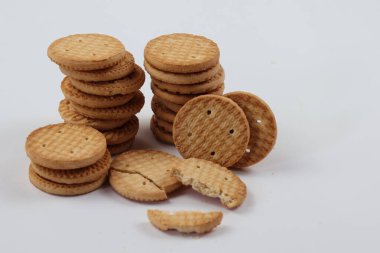 BISCUITS - Bir yığın lezzetli buğday yuvarlak bisküvi beyaz arka planda birkaç kırıntı, lezzetli gevrek yuvarlak krakerler