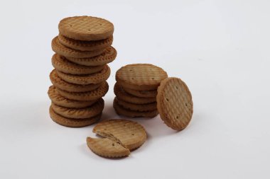 BISCUITS - Bir yığın lezzetli buğday yuvarlak bisküvi beyaz arka planda birkaç kırıntı, lezzetli gevrek yuvarlak krakerler