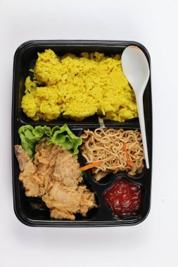 Beyaz arka planda izole edilmiş bir bento kutusunda sarı pirinç ya da Nasi kuning. Sarı pirinç, Hindistan cevizi sütü ve zerdeçal ile pişirilmiş Endonezya kokulu pirinç tabağıdır..