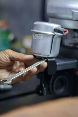 Close up of mechanic's hand measuring and ensuring turbocharger actuator is working properly by blowing pressurized air. clipart