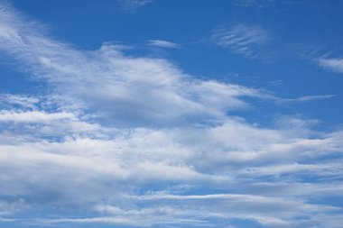 Açık mavi gökyüzü ve birkaç bulut. Gökyüzü çok parlak ve bulutlar her yere dağılmış, mavi gökyüzü beyaz bulutlu arka plan.