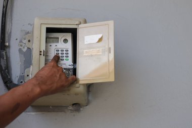 Balikpapan-Endonezya 3. 2025 Asyalı adamın eve elektrik fişi yerleştirmesini kapatın.