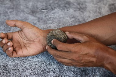 Gri arkaplanda izole edilmiş gri kaplıca taşı ile ovma elini kapat, deriyi temizle..