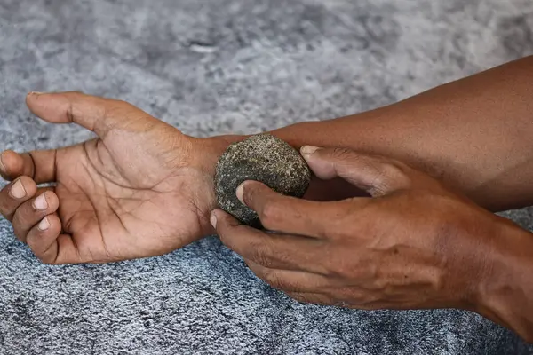 Gri arkaplanda izole edilmiş gri kaplıca taşı ile ovma elini kapat, deriyi temizle..
