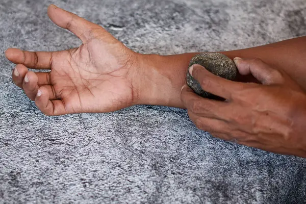 Gri arkaplanda izole edilmiş gri kaplıca taşı ile ovma elini kapat, deriyi temizle..