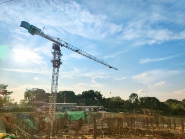 Balikpapan-Endonezya Mayıs 04.2025 güneşli bir günde çalışan kule vinci. Mavi gökyüzünde bulutlar var. Yeni inşaat alanında çalışan inşaat alanındaki vinçler.