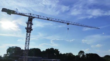 Balikpapan-Endonezya Mayıs 04.2025 güneşli bir günde çalışan kule vinci. Mavi gökyüzünde bulutlar var. Yeni inşaat alanında çalışan inşaat alanındaki vinçler.