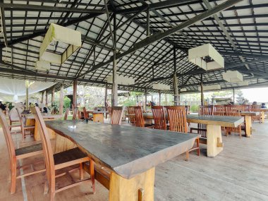 Balikpapan-Endonezya, 10,2025 Modern restoran, uzun ahşap masalar, sandalyeler ve döşemeler. Çevresel atmosfer, kırsal iç tasarım.