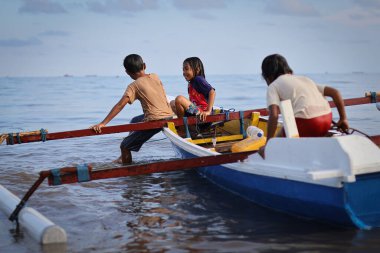 Balikpapan-Endonezya 11 Mayıs 2025 Çocuklar denizde ahşap bir teknede neşeyle oynuyorlar, birlikte kumsalda oynuyorlar, geleneksel ahşap bir tekneye biniyorlar, birlikte eğleniyorlar..