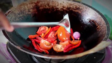 Asyalı kadın Fry 'a acı biber, domates ve arpacık soğanı gibi malzemeyi verir. Chili sosu yapma süreci.