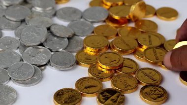 Erkek el, beyaz bir masaya saçılmış altın paraları toplar..