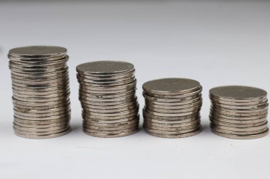 Üstüste yığılmış gümüş paralar beyaz arkaplanda izole edilmiş farklı pozisyonlardadırlar..