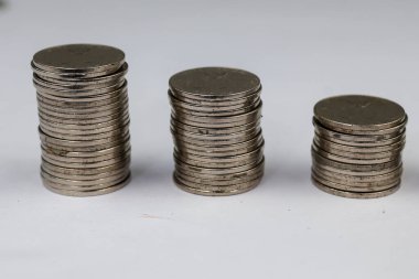 Üstüste yığılmış gümüş paralar beyaz arkaplanda izole edilmiş farklı pozisyonlardadırlar..